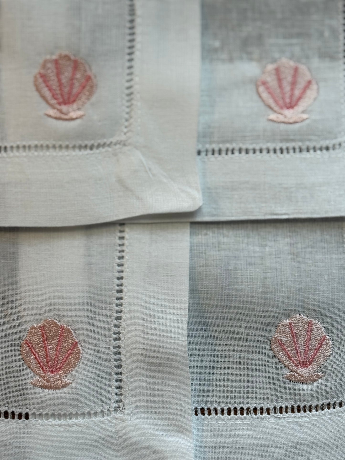 Set of white cotton napkins with pink shell embroidery design.